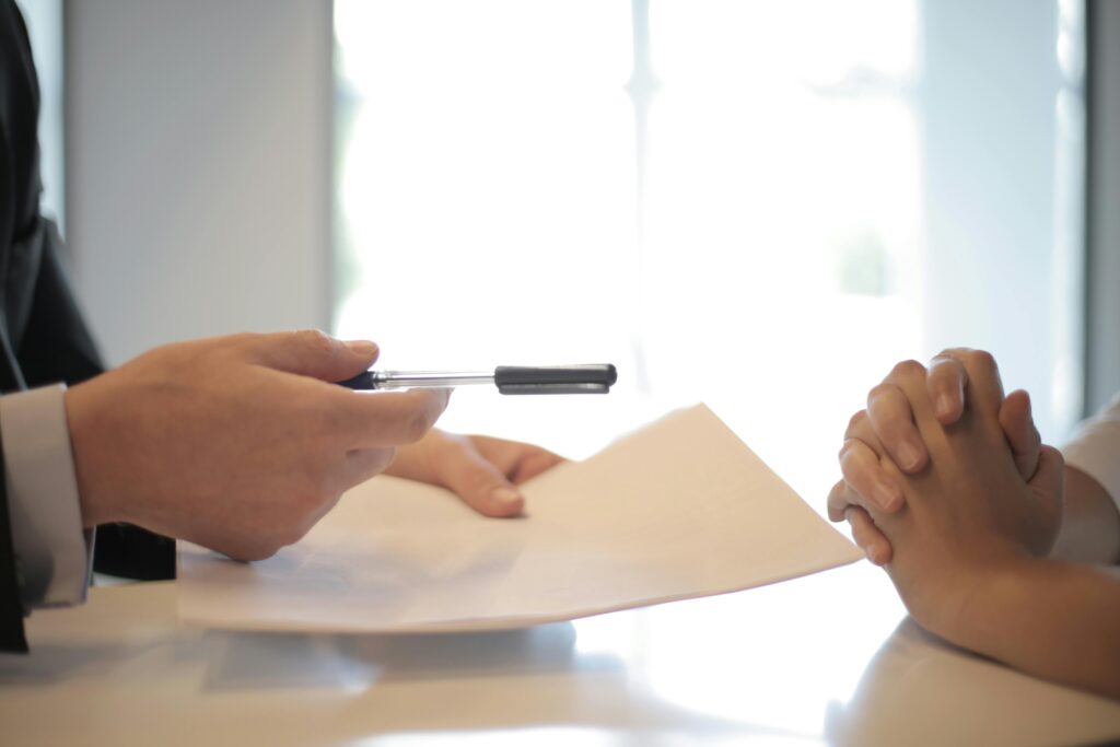 A person handing a pen and paper to another individual during a meeting at MWO.