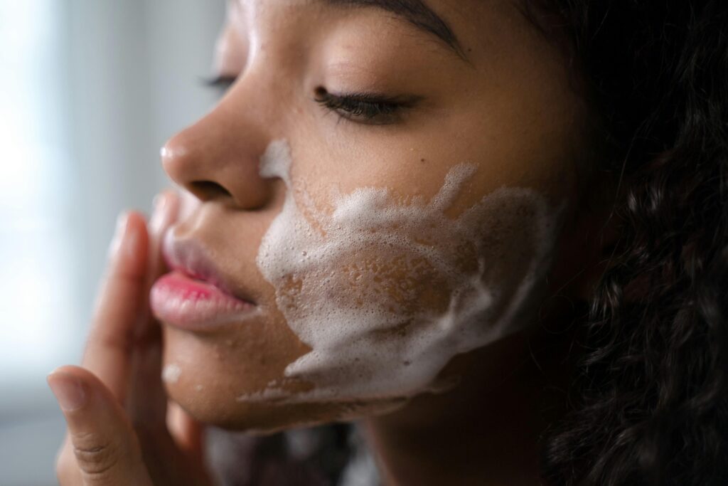 A woman washing her face with a foamy cleanser.