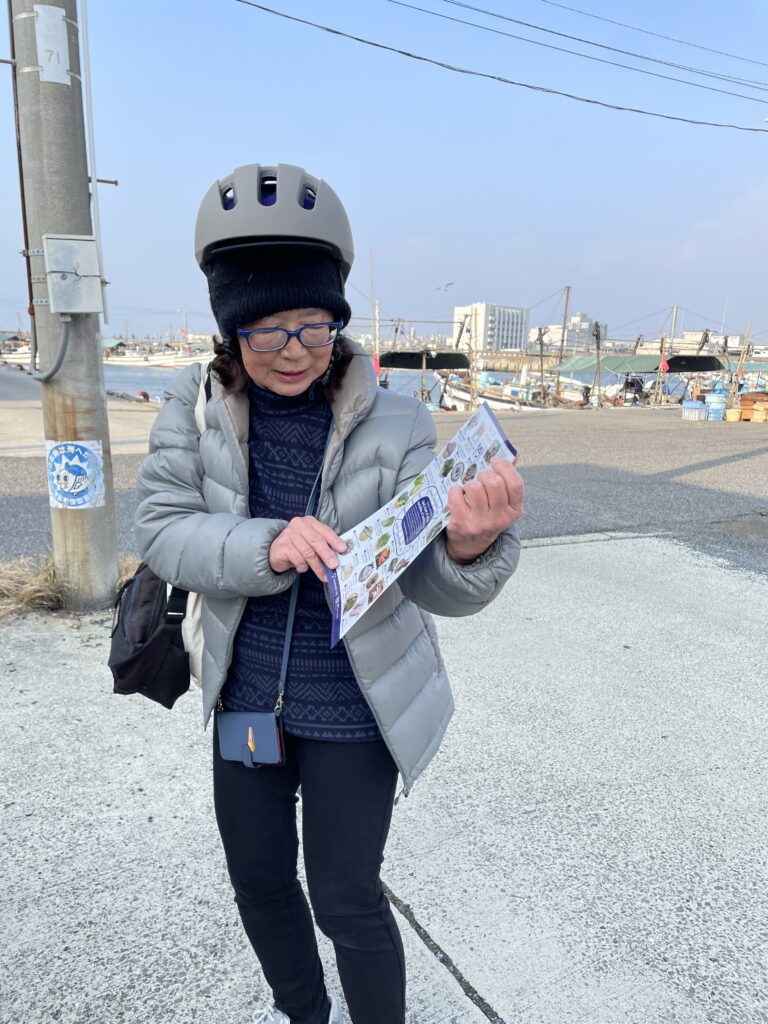 A smiling woman and a tour guide, both wearing helmets, posing for a selfie in front of Jozenji Temple.