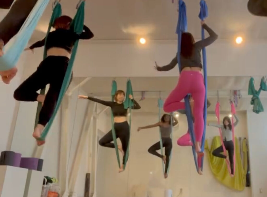  Students resting comfortably in silk hammocks, gently suspended in relaxation during the cooldown.