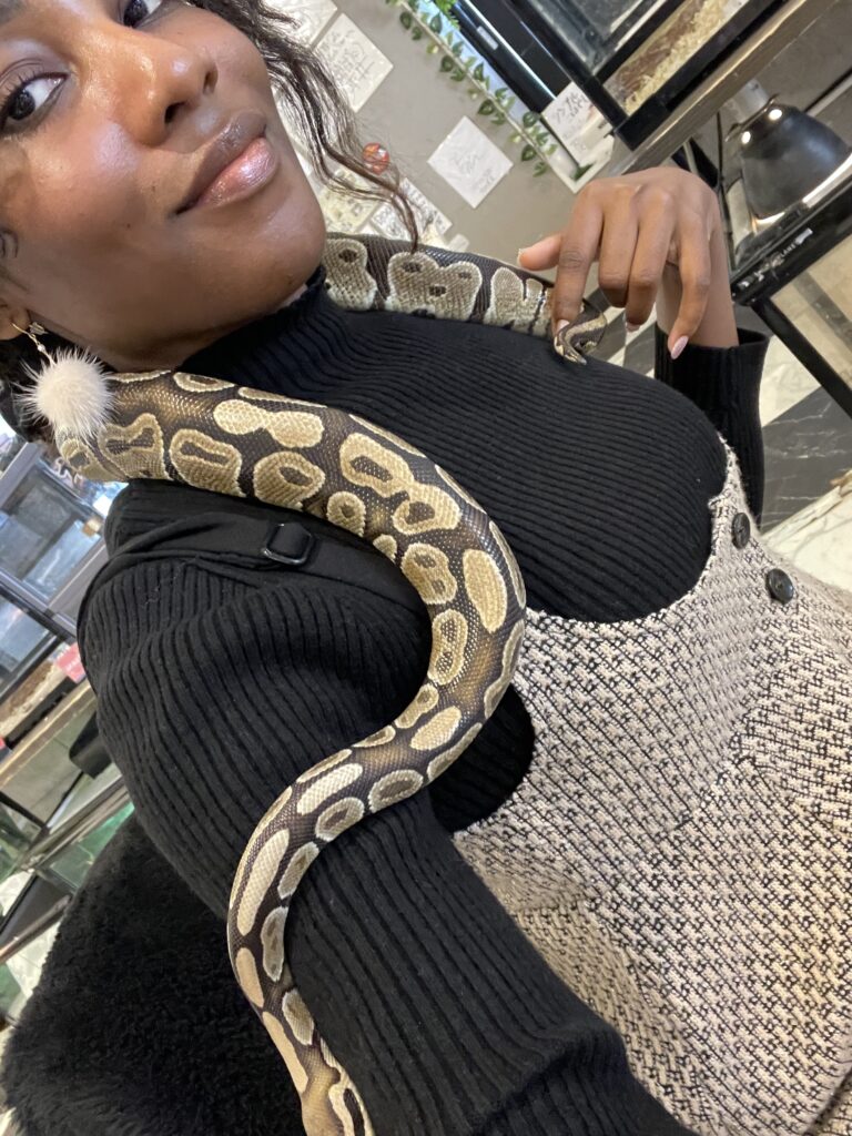 A smiling woman posing with a snake draped gently over her shoulders at ROCKSTAR Café.