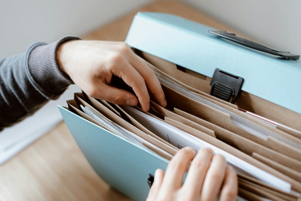 A close-up of a person organizing documents in a blue file folder.