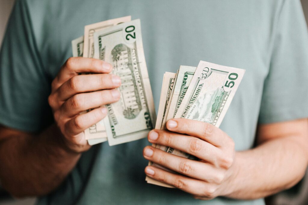 A person counting US dollar bills in their hands.