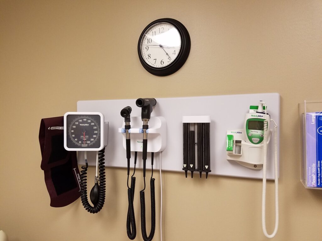 A sleep doctor’s examination room with medical equipment on the wall, including a blood pressure monitor and otoscope.