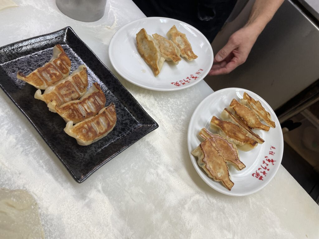  Three plates of freshly pan-fried gyoza on a Kobe restaurant counter.