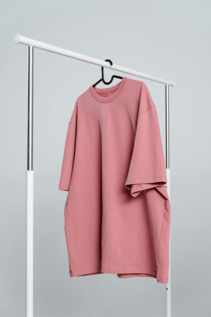 A large pink oversized T-shirt hanging on a clothing rack.