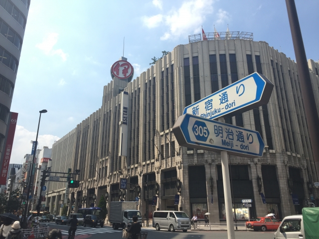 The exterior of Isetan department store in Shinjuku, Tokyo, with street signs in the foreground.