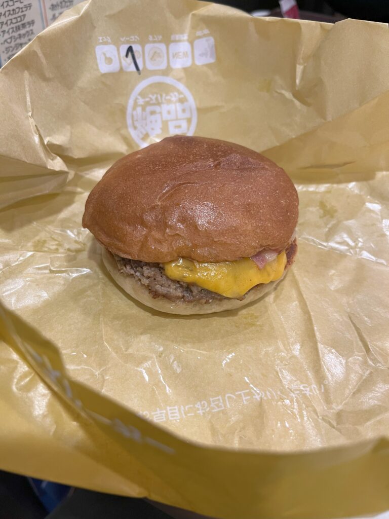 A McDonald's cheeseburger wrapped in yellow paper.