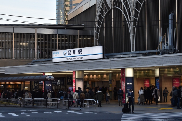 The entrance to JR Shinagawa Station, bustling with commuters and travelers, with signage in both Japanese and English.