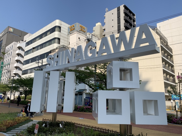 A large, stylized "Shinagawa" sign in an outdoor plaza, surrounded by greenery and modern buildings.