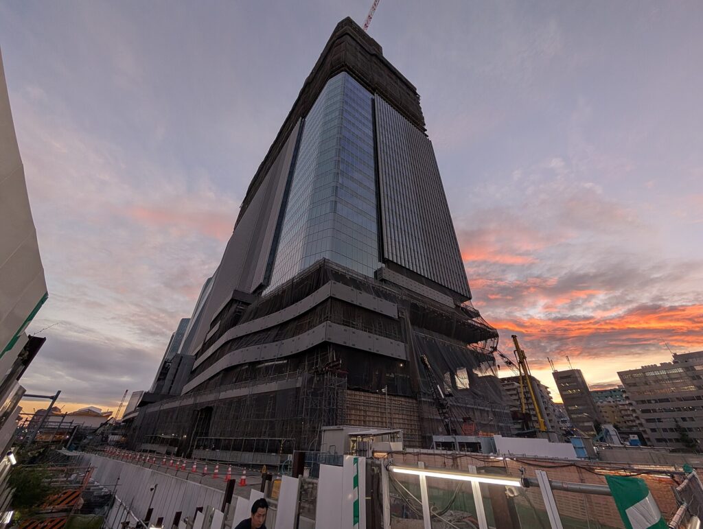 Takanawa Gateway Tower under construction at sunset.