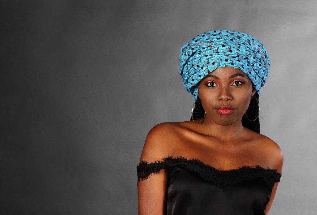 Woman in a blue headwrap posing confidently, showcasing protective hair style.