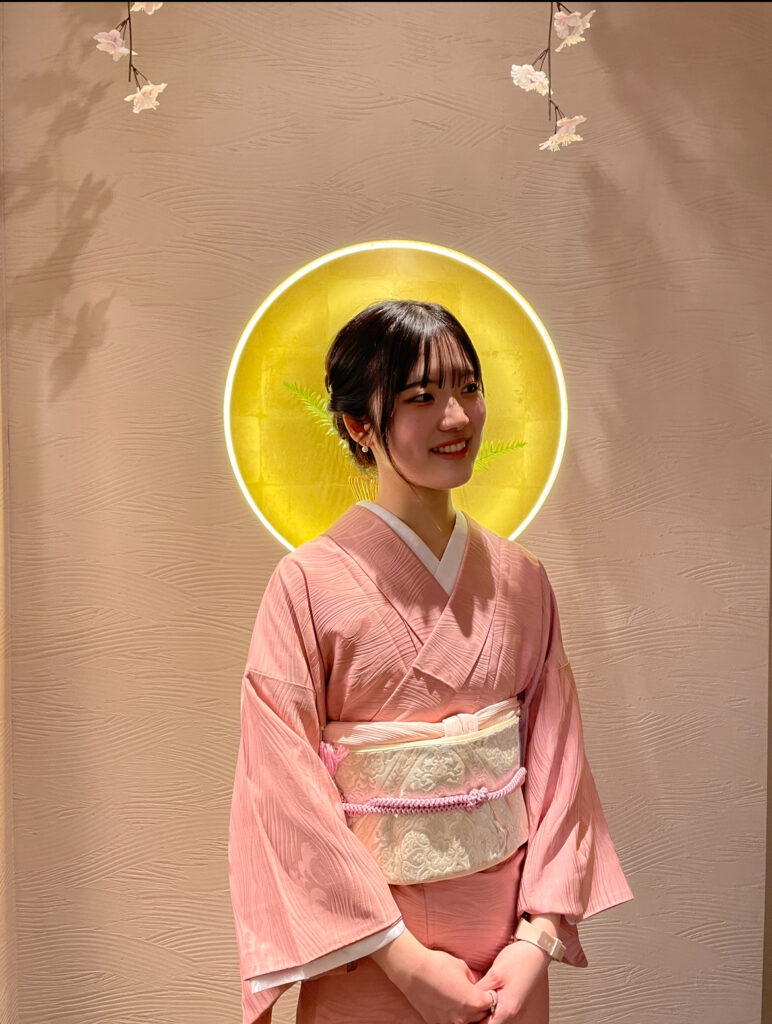 Woman in traditional kimono at Sazanka Osaka with glowing yellow light behind her.