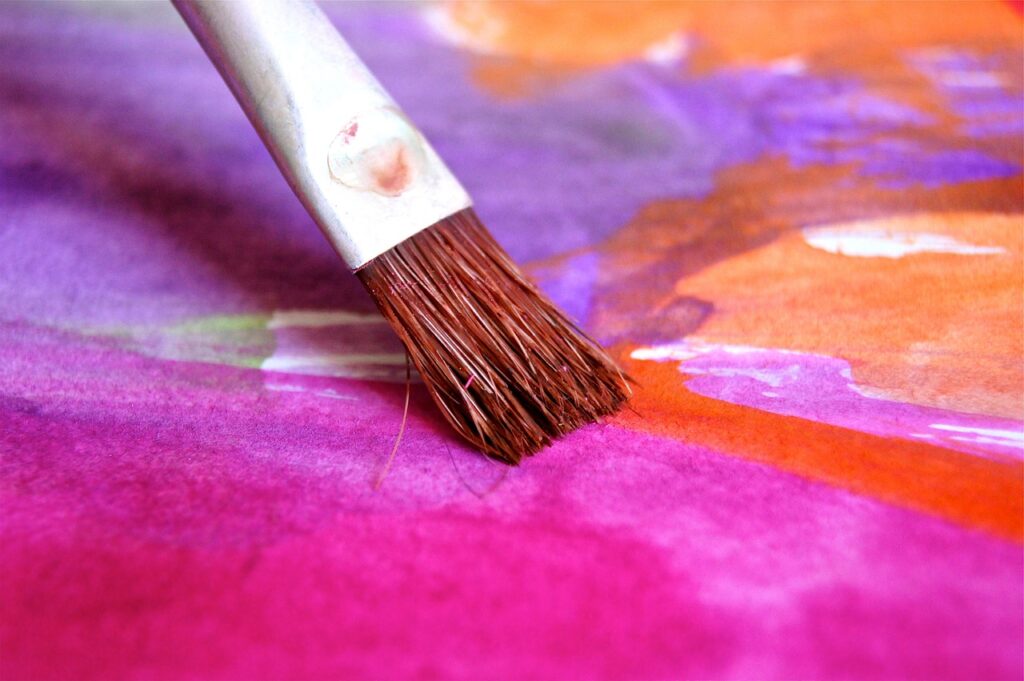 Paintbrush on a vibrant watercolor canvas for a paint and sip session 
