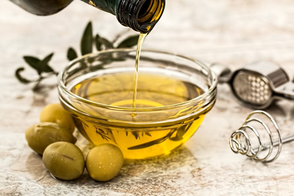 Olive oil being poured into a bowl, perfect for moisturizing hair treatments.