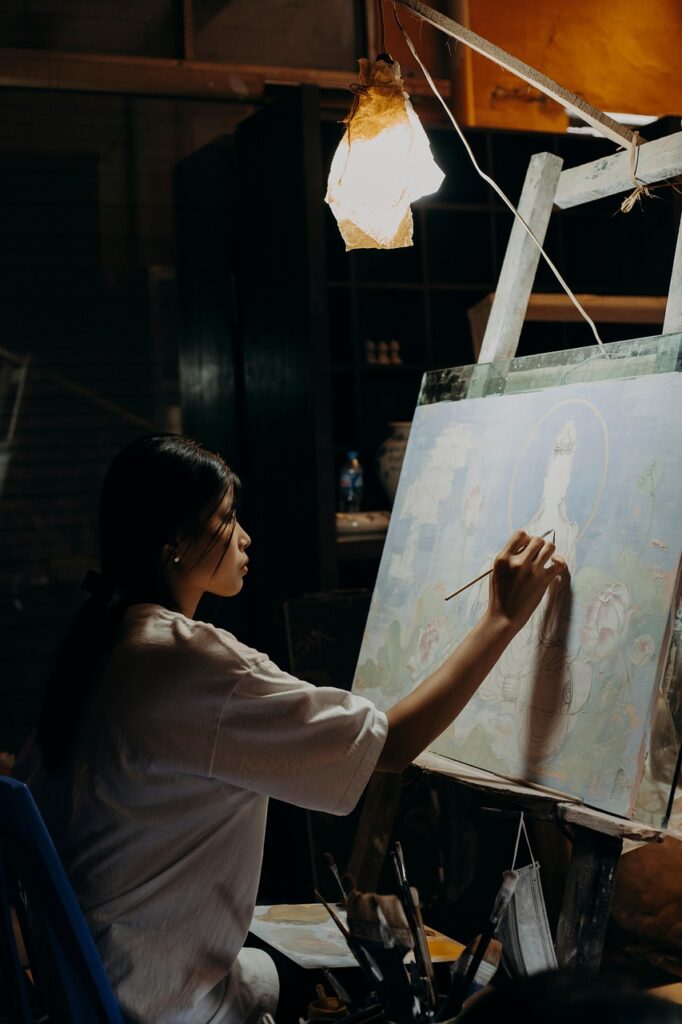 Woman painting in a dimly lit private studio, representing Semba Art Studio in Osaka