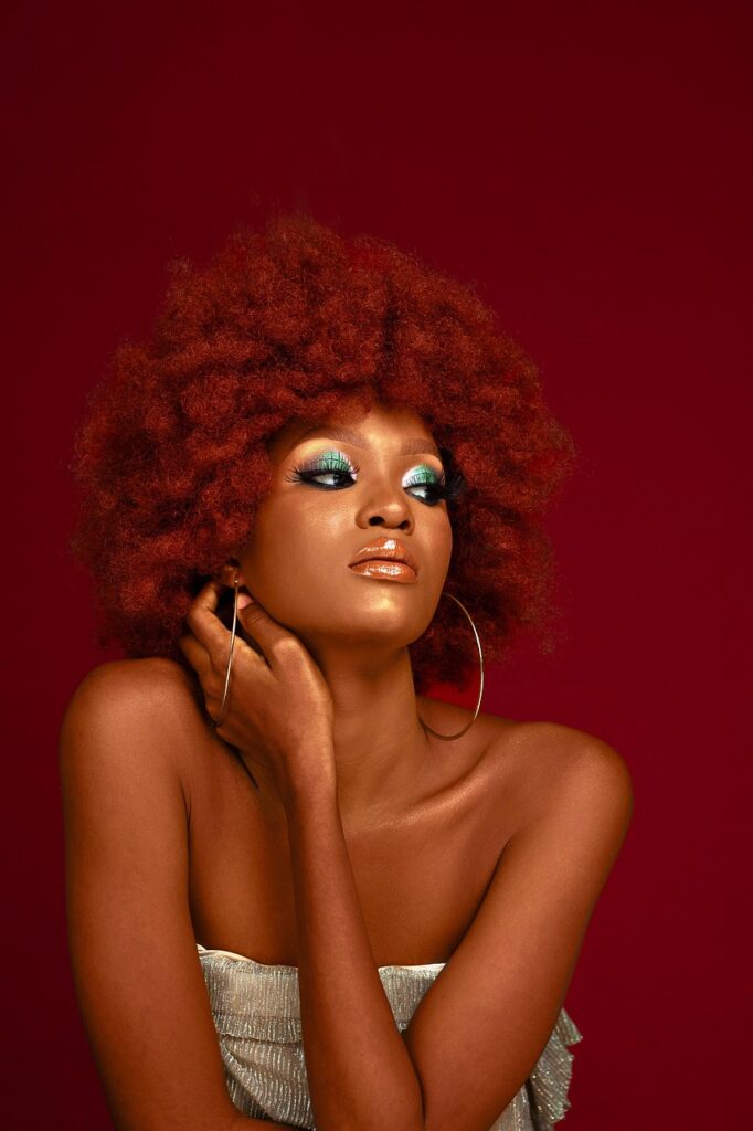 Woman with a vibrant red afro and glowing skin, showing off healthy natural hair.