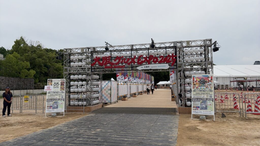 Numbered vendor stalls at the Osaka expo featuring menus with photos and digital payment options.