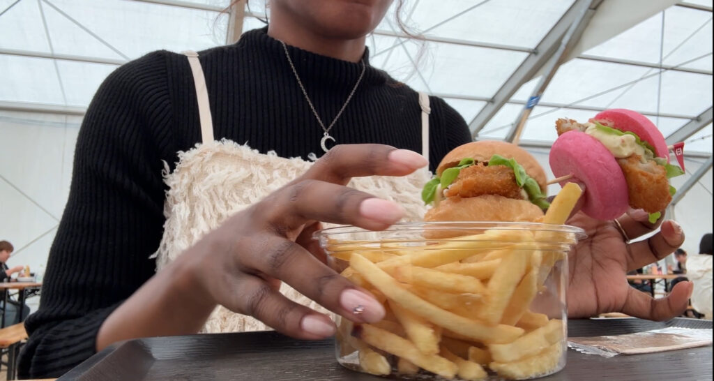 Woman holding a tray with fries and colorful mini burgers at the Osaka Gourmet Expo.