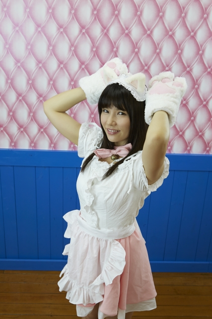 Woman dressed in a maid outfit at a maid cafe in Akihabara, posing with playful expression.