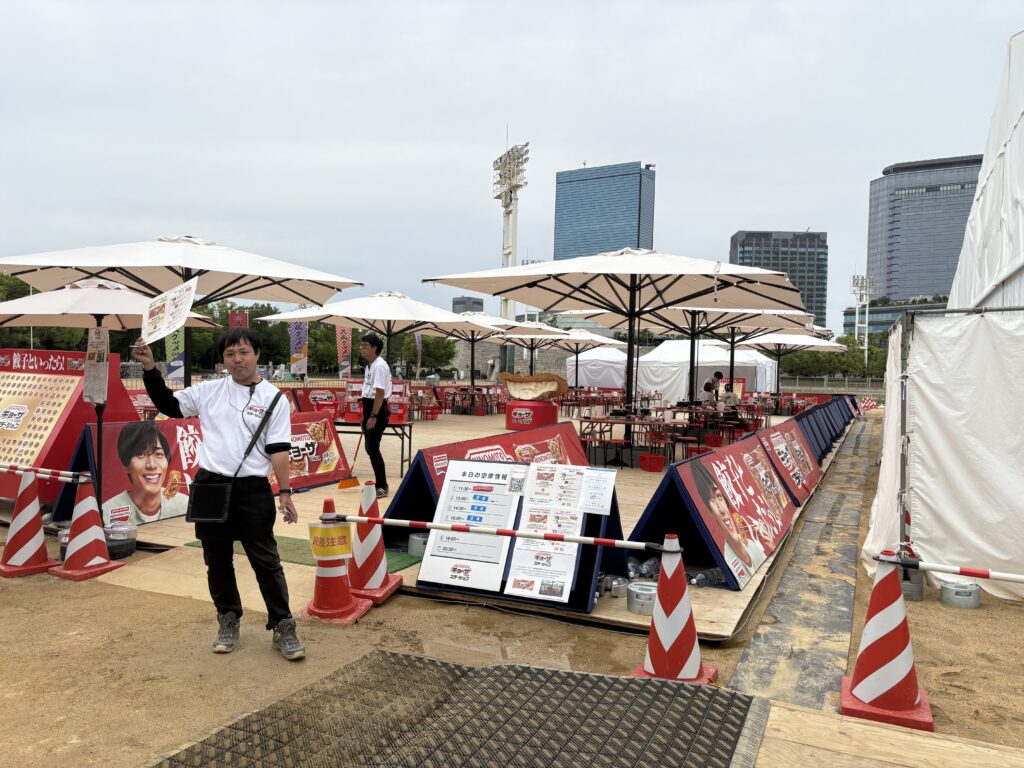 Outdoor seating area with parasols at the Osaka food event, with staff assisting guests.