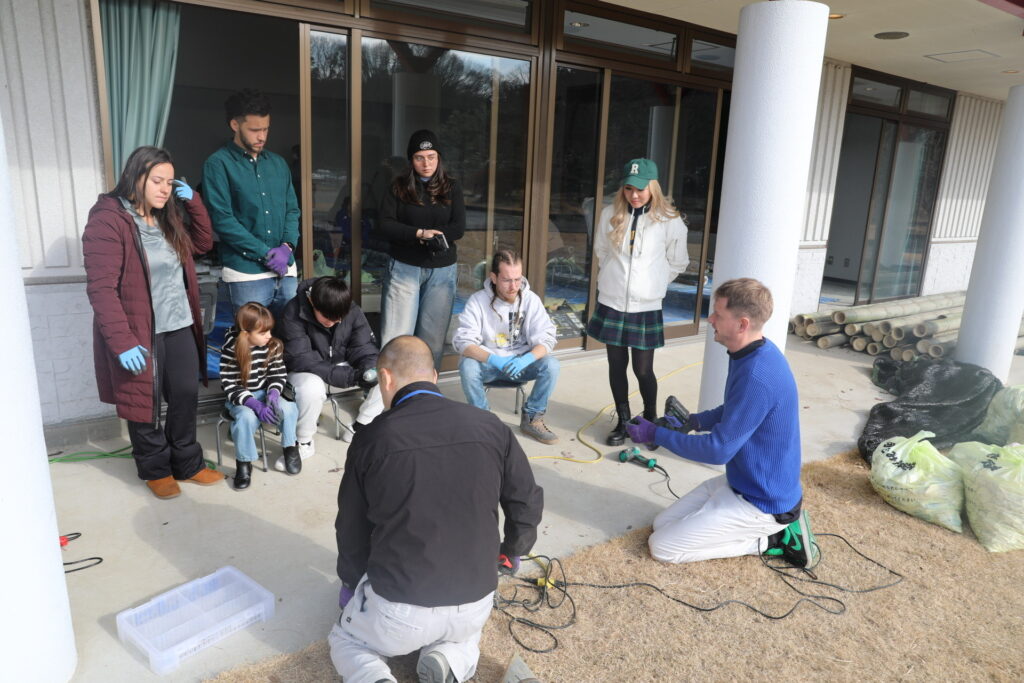 Christopher conducting an outdoor DIY workshop with international volunteers and families at Elm Resort.
