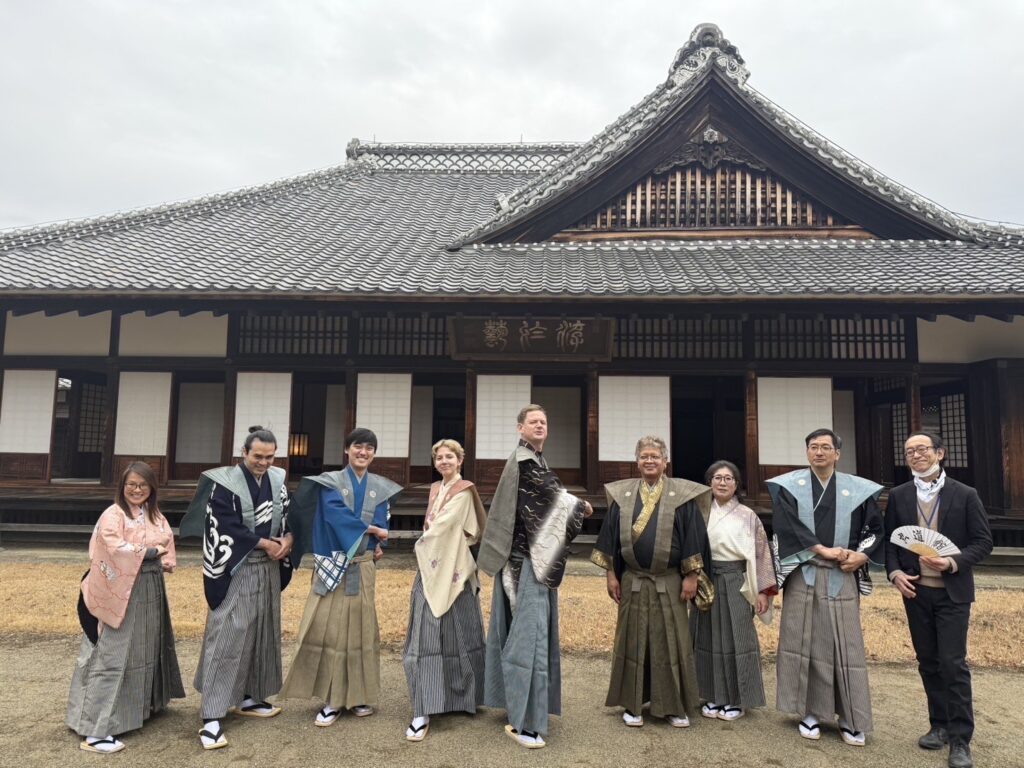 Christopher and a group of locals and foreigners dressed in traditional Japanese kimono standing in front of a historic building.