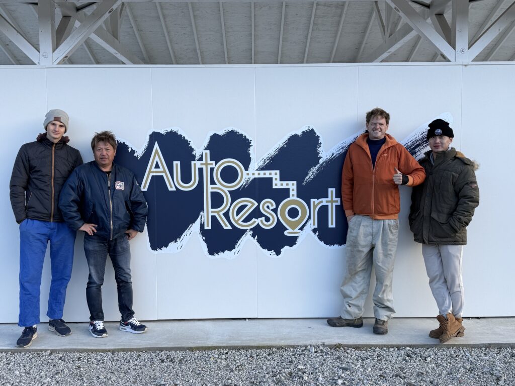 Christopher and his collaborators standing in front of the Auto Resort sign in Ibaraki.