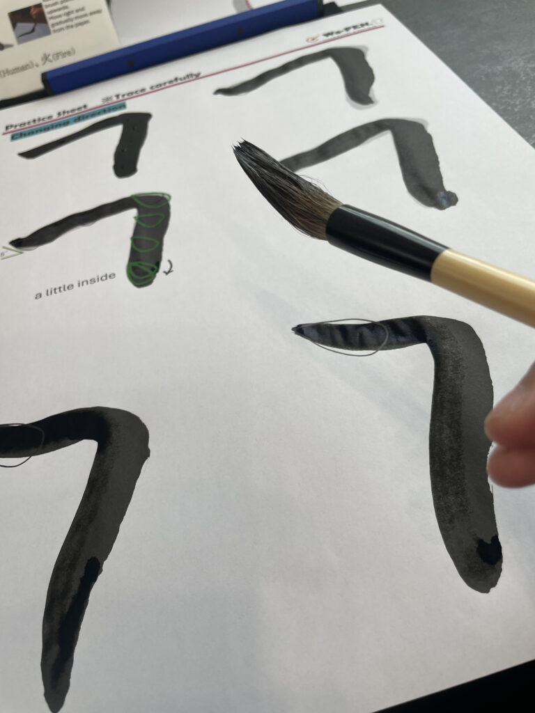 Guests practicing Japanese calligraphy at Wa-Pen Calligraphy while an instructor observes and guides.