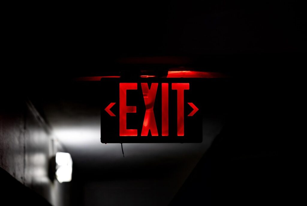 Illuminated red exit sign in a dark hallway.
