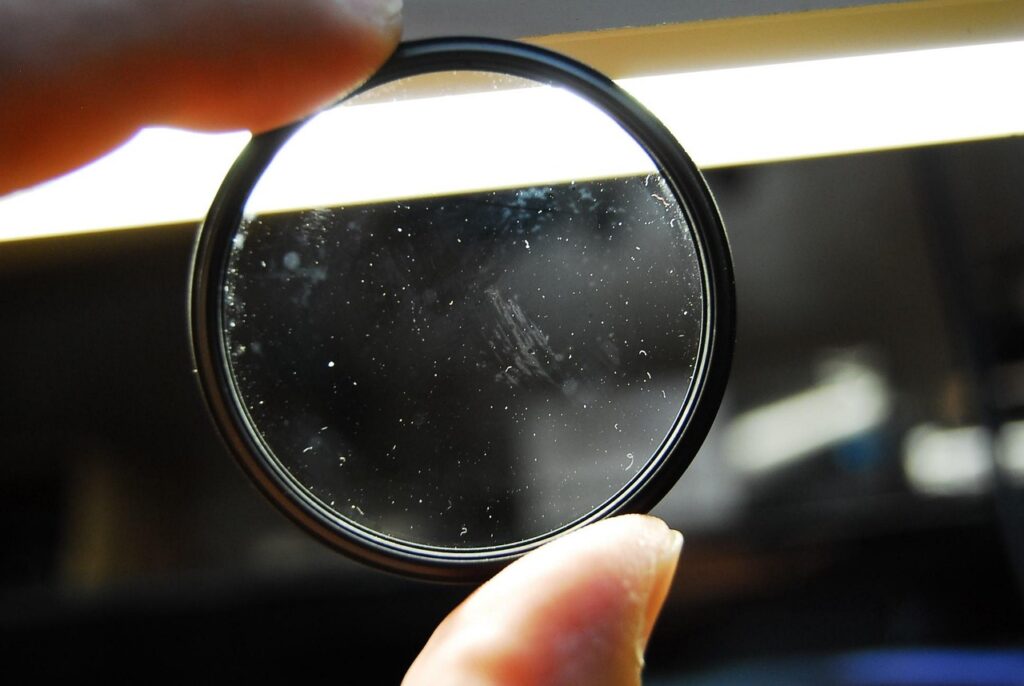 Mold and dust particles visible on a circular lens under a light
