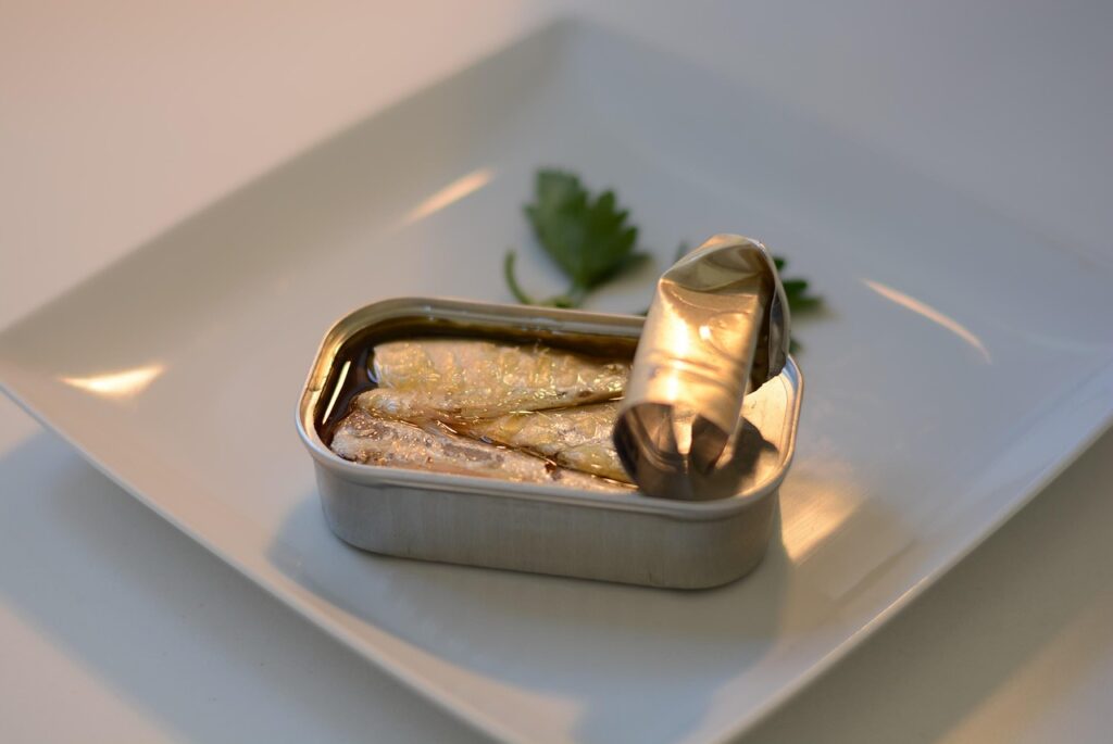 Open can of sardines on a white plate