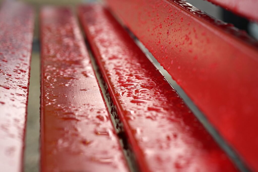 Red bench covered with rain droplets