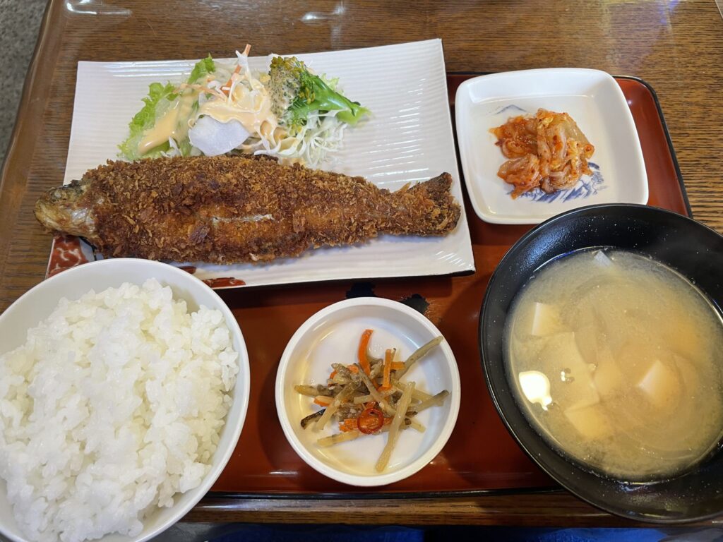 A Japanese set meal featuring crispy fried fish, miso soup, white rice, and assorted side dishes.