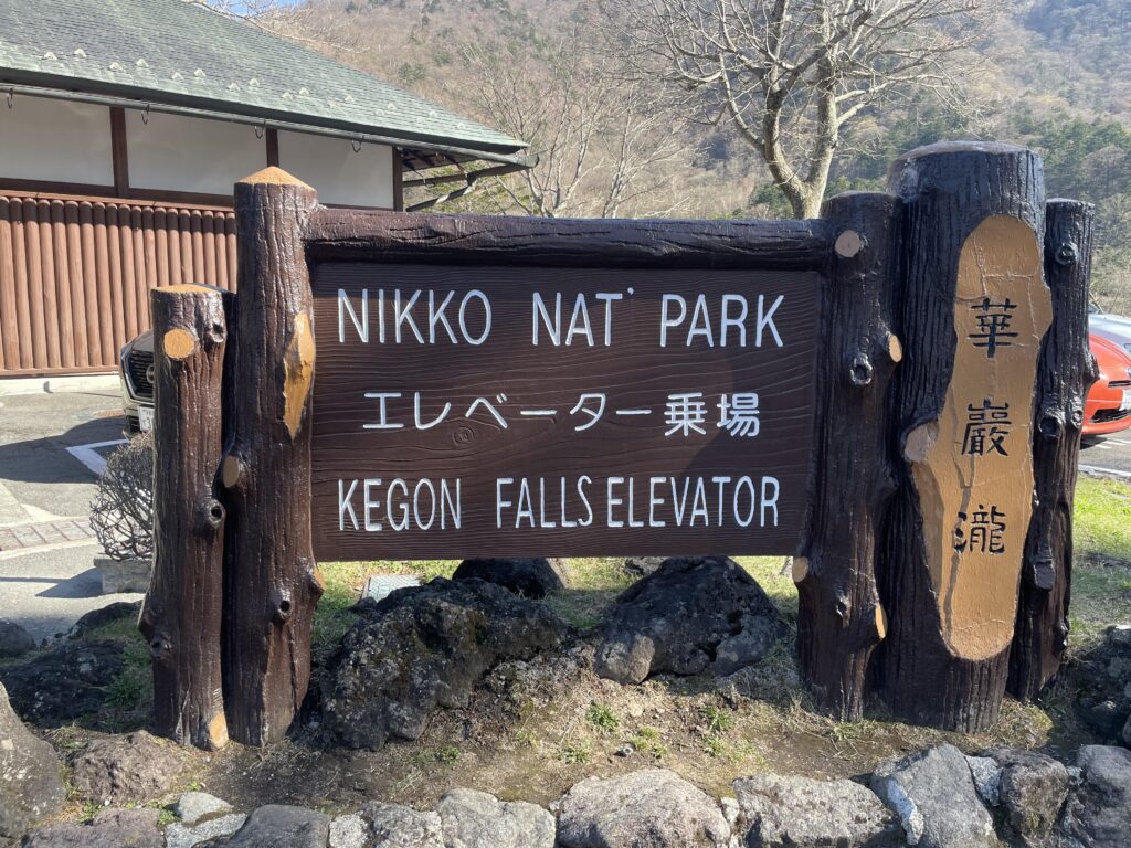 A wooden sign reading “Nikko Nat’l Park - Kegon Falls Elevator” in English and Japanese.