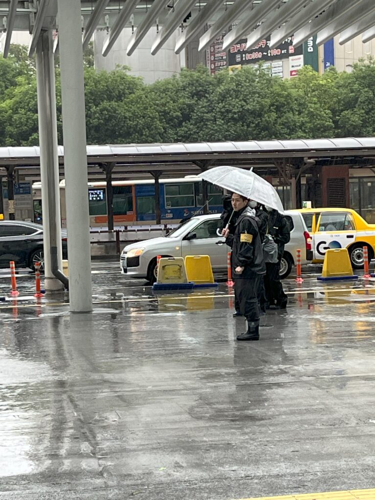 Person in rain gear holding a transparent umbrella on a wet Tokyo street