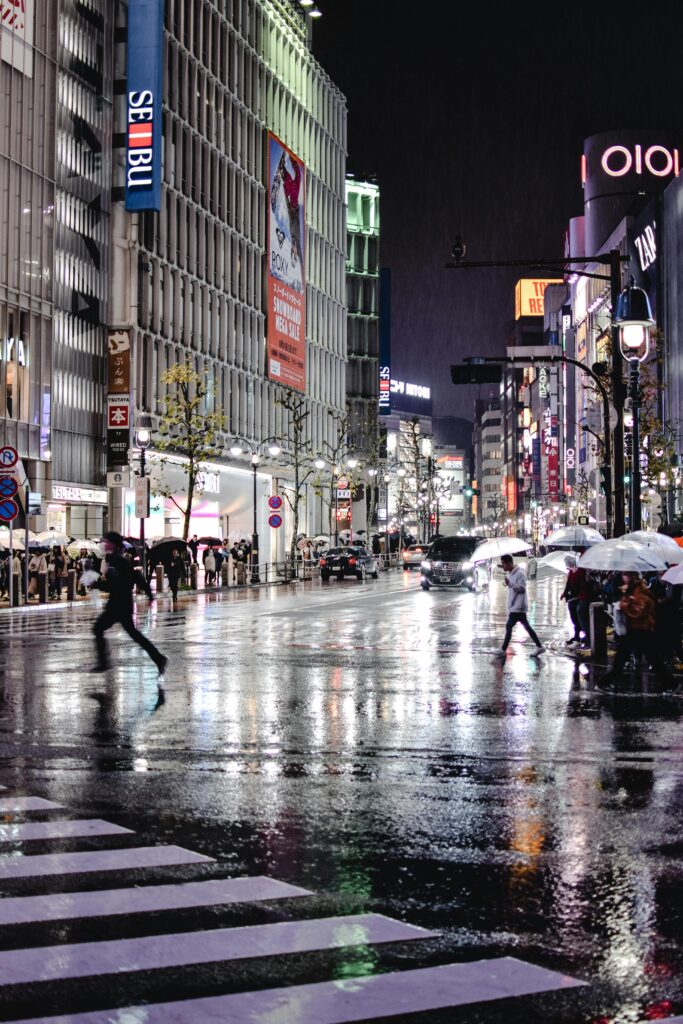 People walking with umbrellas in the rain in a busy Tokyo street.