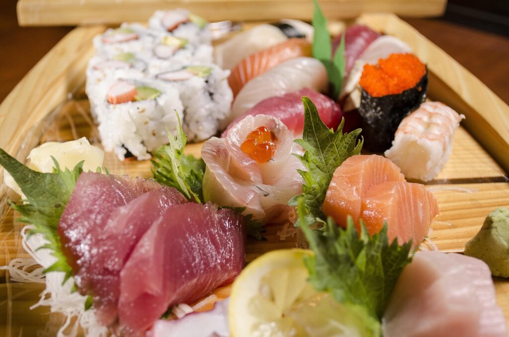 Assorted nigiri sushi set on a wooden tray with soy sauce and wasabi, ready to eat