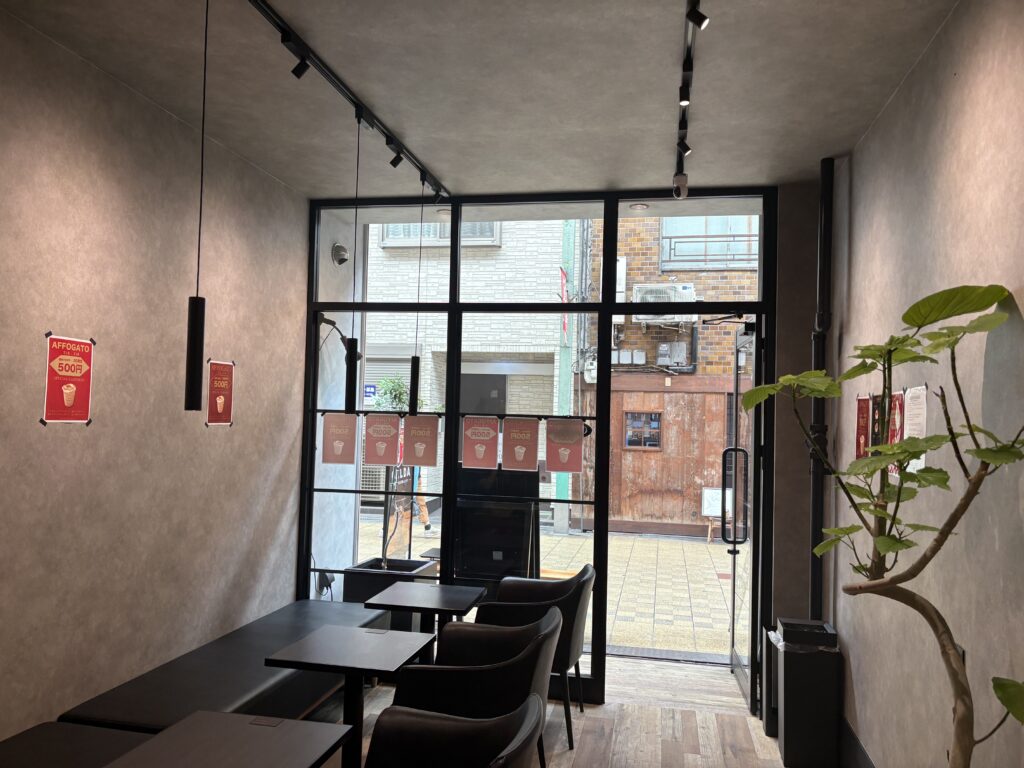 Minimalist, modern seating inside CALDA Affogato Café in Nakazakicho with soft lighting and a potted plant by the wall.