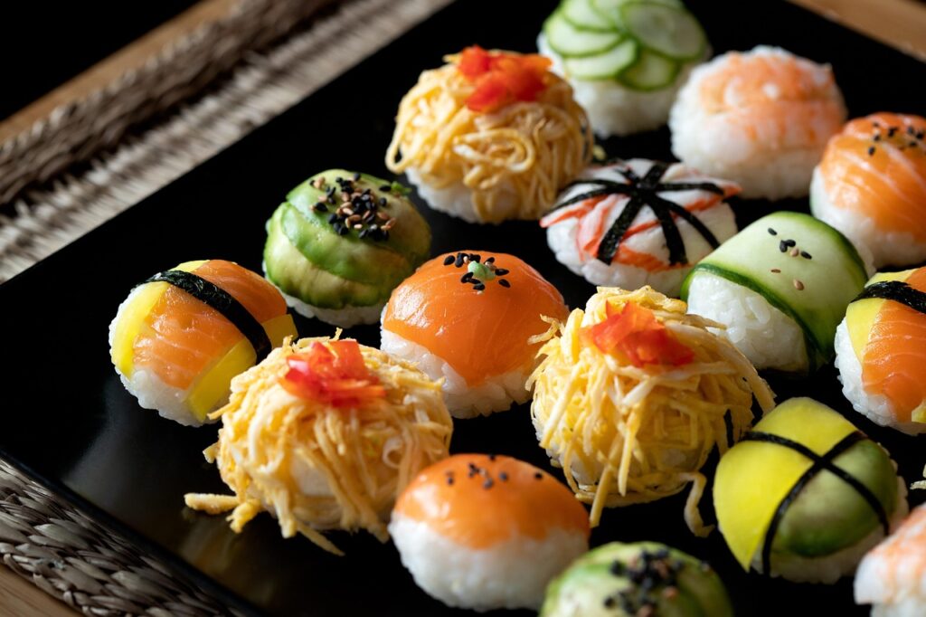 Colorful temari sushi balls with assorted toppings on a black tray