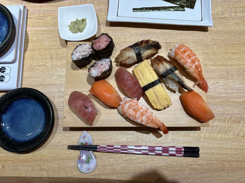 Grilled eel nigiri and inari sushi on a dark rectangular plate 