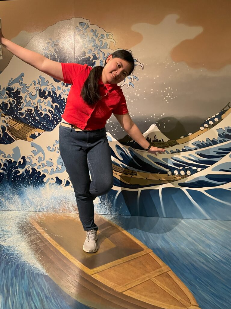  A woman balancing on an illusion of a boat riding The Great Wave off Kanagawa.