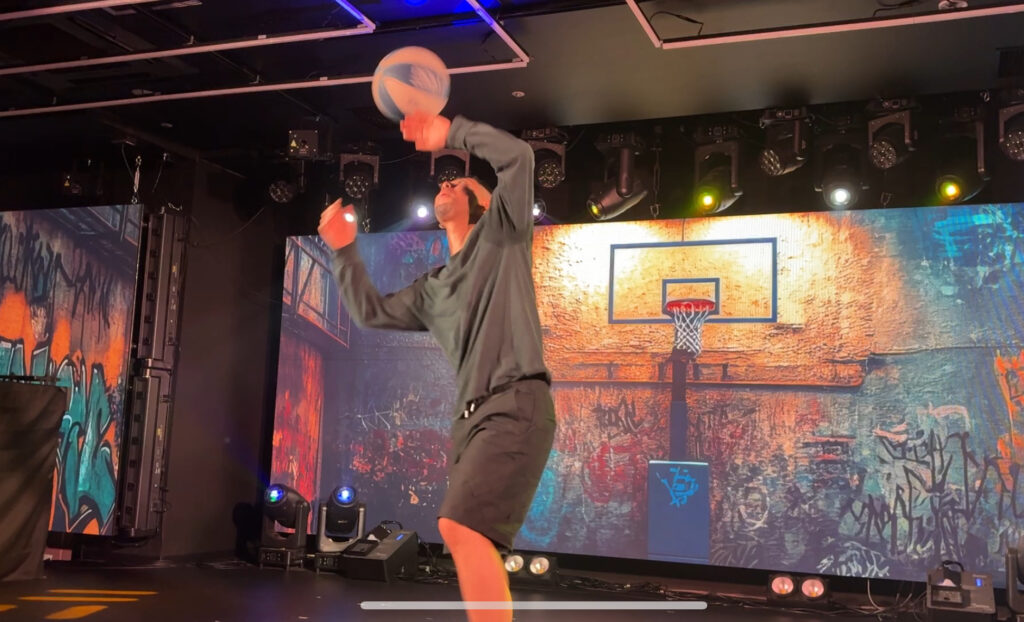 Performer doing basketball tricks on stage with urban-themed background