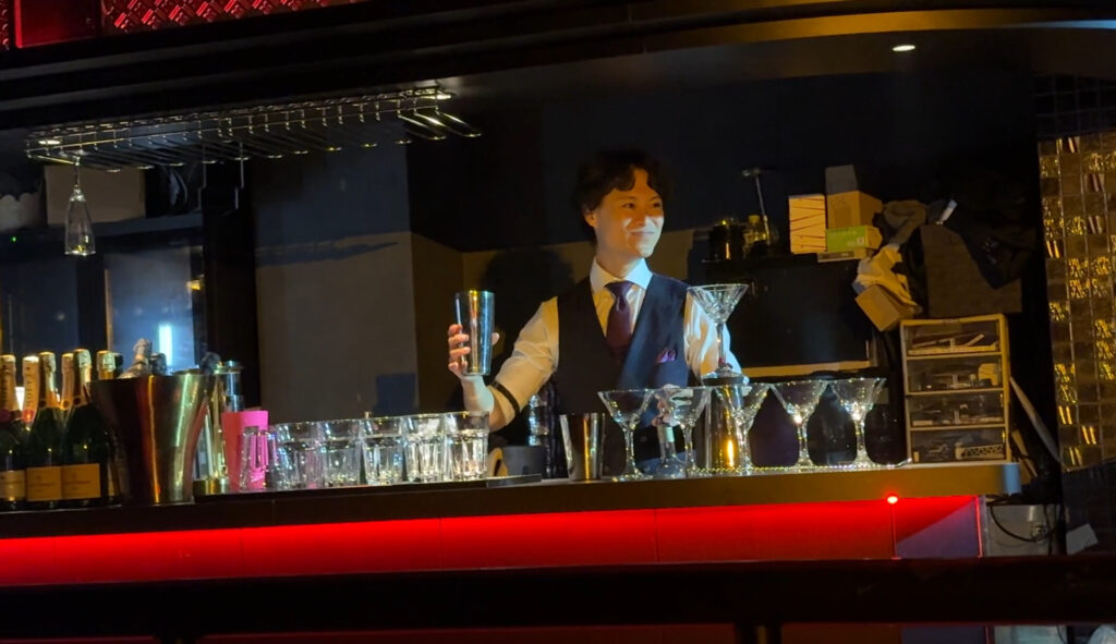 Bartender in a vest and tie preparing cocktails behind a stylish bar