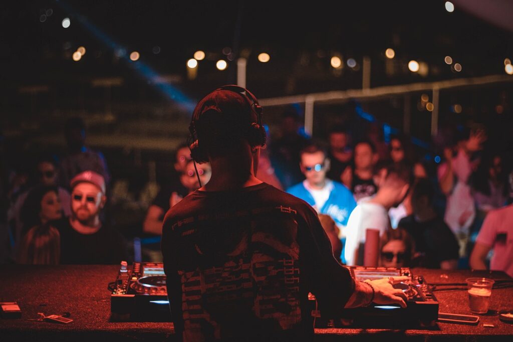 DJ playing music at a club with a crowd of people in the background