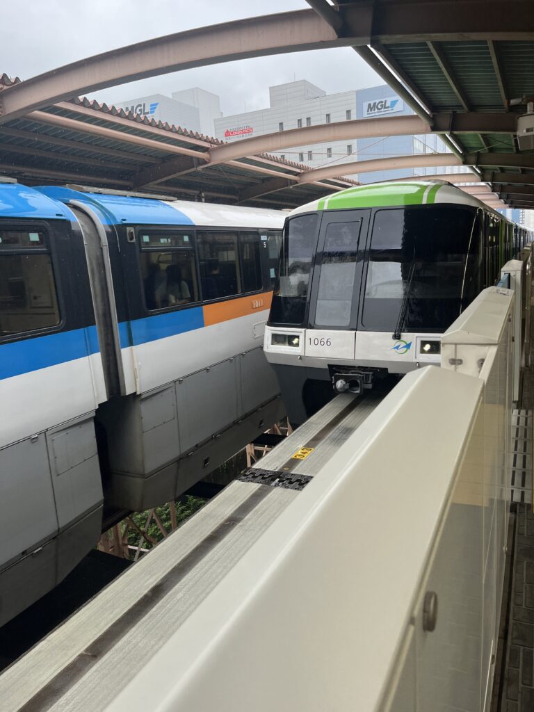 Two Tokyo Monorail trains passing each other on parallel tracks at an elevated platform.