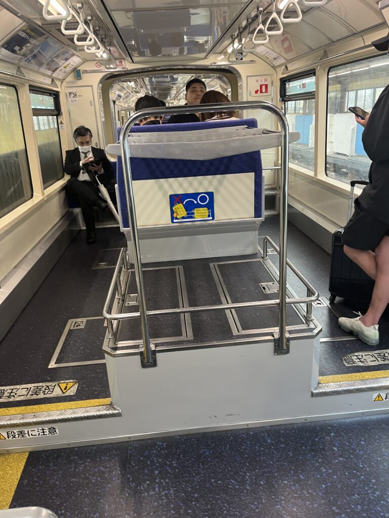 Interior of the Tokyo Monorail with luggage rack and seated passengers,
