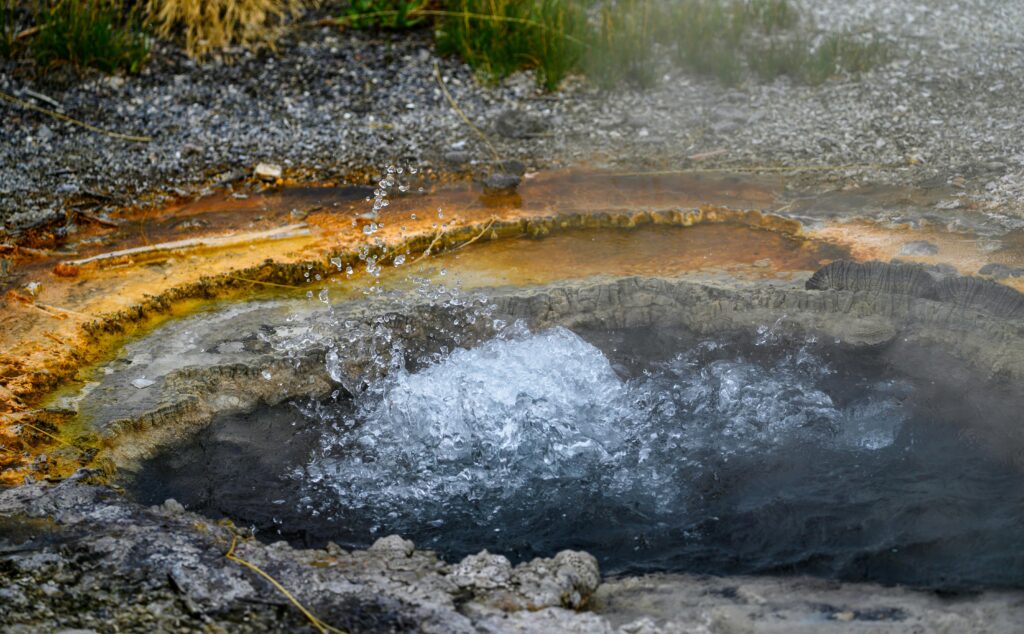 A natural hot spring bubbling up from the earth, surrounded by mineral deposits.