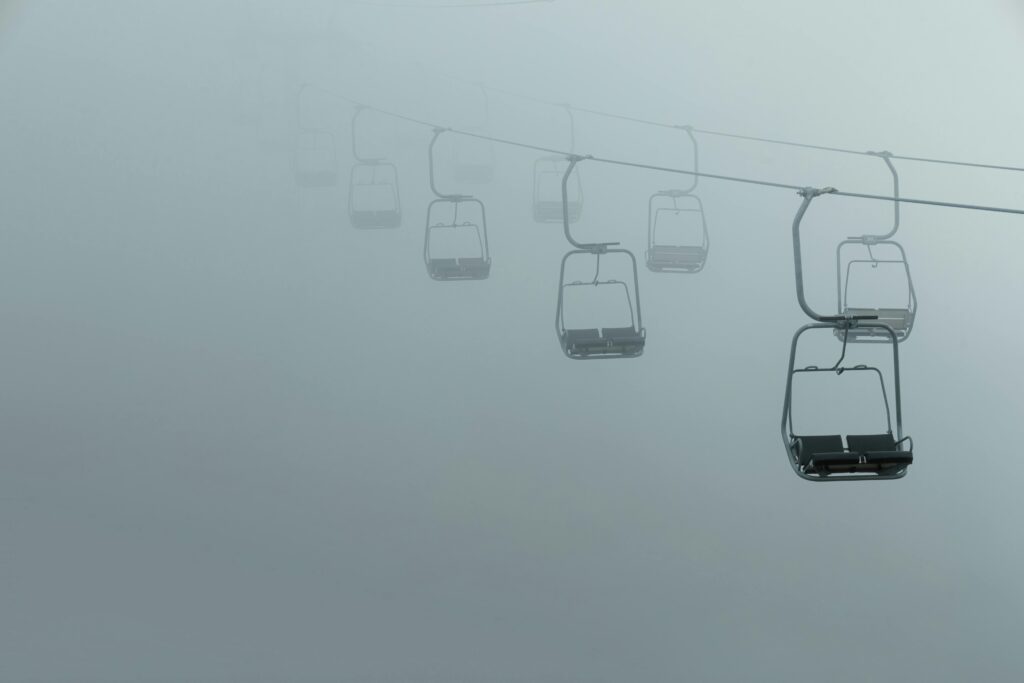 A misty chair lift floats into the fog over Mt. Takao, barely visible in the dense air.