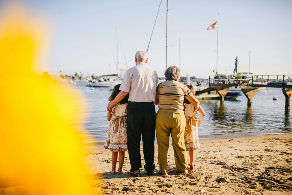 Grandparents with two granddaughters standing by a marina, looking out over the water.